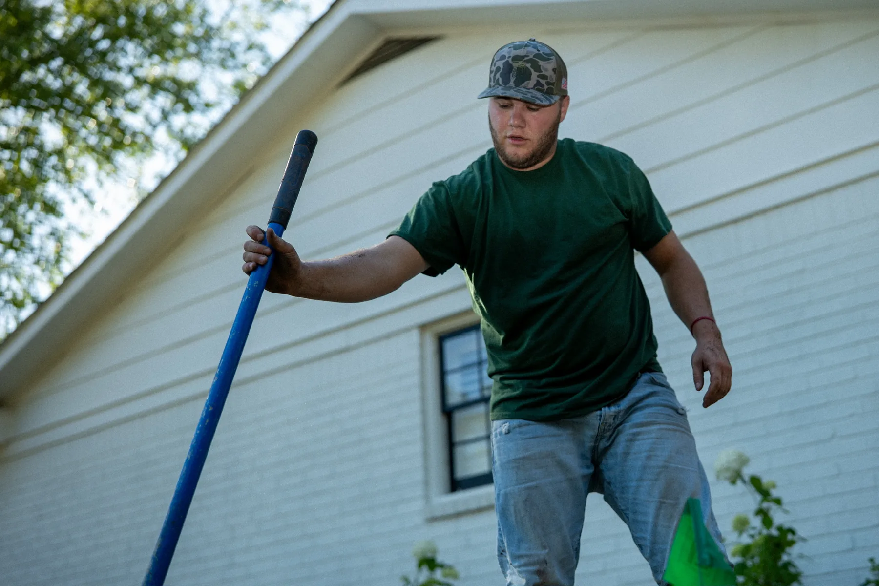 Worker carrying irrigation pipe beside a property